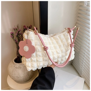 Detail of white bubble texture fabric bag with pink leather tied strap and flower charm