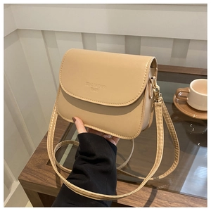 Gros plan sur un petit sac carré beige minimaliste avec texte embossé et doré