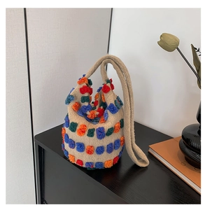 Detail of knit bucket bag with colorful 3D dots and thick shoulder strap on black cabinet