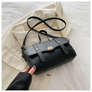 Detail der minimalistischen schwarzen Umhängetasche mit goldenem Schloss auf Blazer