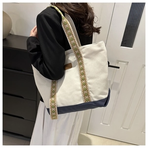 Vue latérale d'un sac cabas en toile avec bandoulières brodées et base bleu marine
