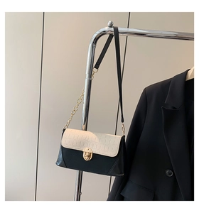 Detail of two-tone baguette bag featuring crocodile texture and gold rotary lock