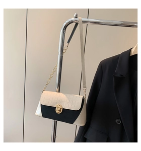 Detail of contrast color baguette bag with crocodile texture and gold metal clasp