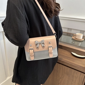 Sac bandoulière bicolore rose et gris avec un nœud en métal porté par un mannequin