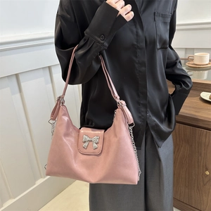 Pink faux leather tote bag with silver bow accent shown in a model photoshoot