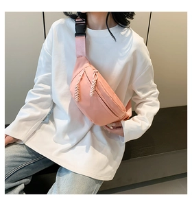Pink nylon crossbody waist bag shown on model with adjustable strap and dual zippers