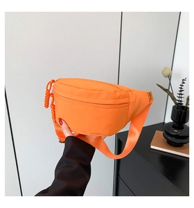 Detail of orange nylon chest bag with woven zipper pull and adjustable strap