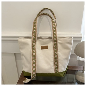Détail du sac fourre-tout en toile avec anses tissées vertes et écusson en cuir