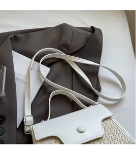 Close-up of woven straw and white leather handbag placed on a brown blazer jacket