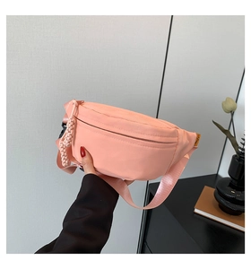 Detailed shot of pink nylon chest bag featuring textured zipper pull and logo tag detail