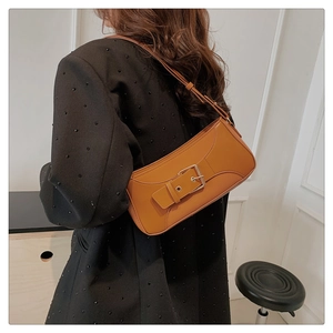 Detail of caramel vintage leather shoulder bag with wide strap and metallic buckle