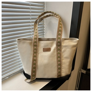 Détail du sac cabas en toile avec anses tissées géométriques vertes et patch en cuir