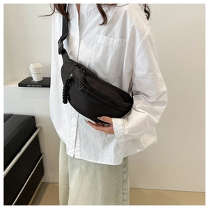 Detail of minimalist black nylon belt bag featuring unique braided zipper pulls