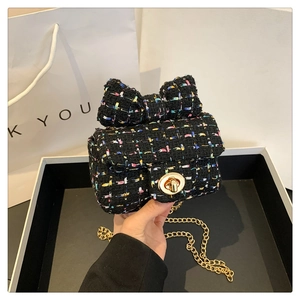 Close-up of black tweed mini bag with bow detail and gold chain strap and buckle