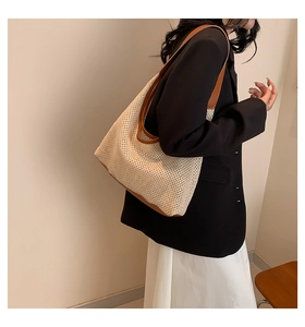 Detail of woven tote bag with brown leather trim and wide shoulder strap on model