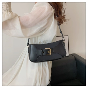 Detail of vintage black faux leather shoulder bag with glossy gold metallic buckle closure