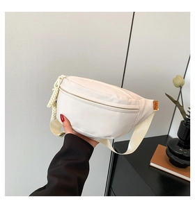 Detail of white nylon chest bag with adjustable woven strap and orange brand label