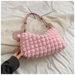Detail of pink bubble texture fabric handbag with flower pendant on a soft bed setting