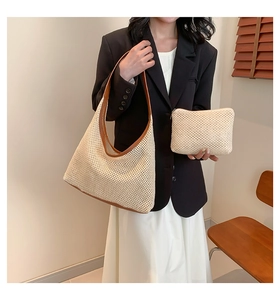 Detail of woven straw hobo tote bag with brown leather trim and matching zip pouch set