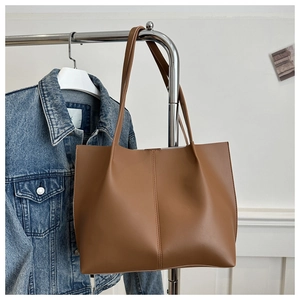 Detailed close-up of a large caramel tote bag with vertical center stitching on a hanger