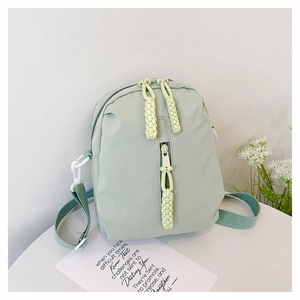 Detail of light mint green nylon crossbody bag with woven zipper pull and adjustable strap