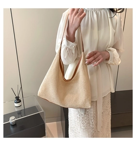 Detail of hollow woven texture and brown leather strap on a beige summer tote bag