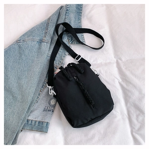 Minimalist black nylon crossbody bag featuring vertical zipper and white plastic hooks