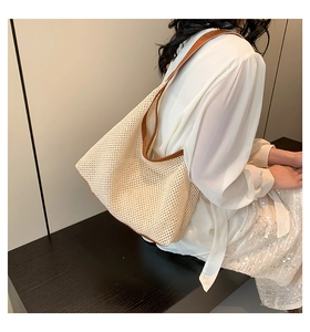 Detail of cream woven tote bag featuring brown leather trim and shoulder strap