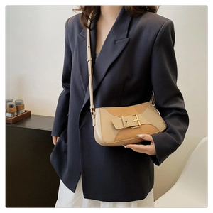 Close-up of contrast color shoulder bag featuring metal buckle and premium leather texture