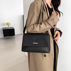 Minimalist black pebbled leather tote bag with a striped wide strap on a model