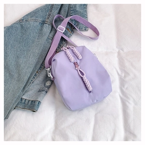 Detail of lavender nylon crossbody bag showing vertical zipper and adjustable shoulder strap