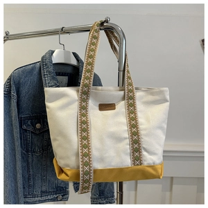 Détail du sac cabas en toile montrant l'étiquette en cuir et les bretelles jacquard
