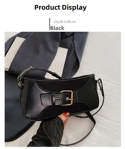 Detail of a black leather underarm bag featuring a gold square metal buckle design