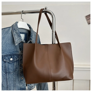 Detail of a brown leather tote bag showing smooth texture and central vertical stitching