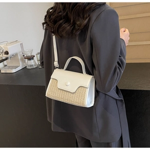Detail of white leather and woven straw crossbody bag shown in a minimalist cafe setting