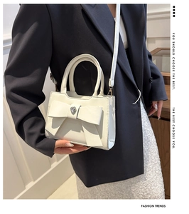 Dettaglio mini borsa bianca con fiocco, decoro a cuore di diamanti e manico corto