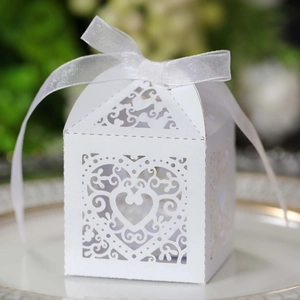 Laser cut white heart wedding favor box with organza ribbon on a decorative plate