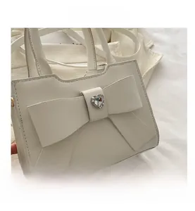Dettaglio della borsa in pelle bianca opaca con fiocco e cristallo a forma di cuore