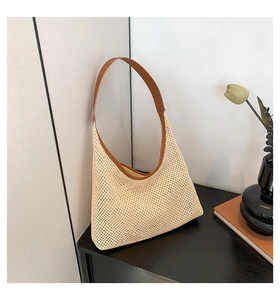 Detailed close-up of woven straw tote bag with brown leather strap in a minimalist setting