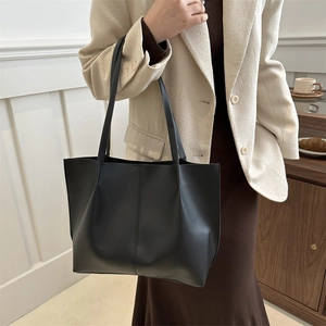 Minimalist black large capacity leather tote bag for women shown in a casual lifestyle setting
