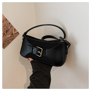 Detail of black vintage baguette bag featuring a large metal buckle and adjustable strap