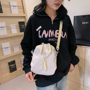Minimalist nylon crossbody bag in cream white with adjustable straps and yellow zipper pulls