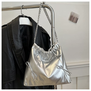 Détail du sac cabas argenté métallisé avec nœuds décoratifs et bandoulière chaîne