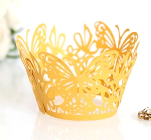 Macro detail of laser-cut golden cupcake wrapper featuring butterfly and floral patterns