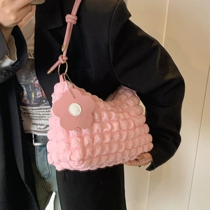 Pink bubble textured pleated shoulder bag with floral pendant on a stylish model