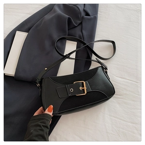 Detail of black underarm bag with gold square buckle and leather texture splicing