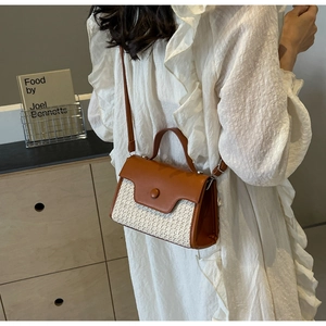 Detail of a brown leather and woven fabric crossbody bag with circular magnetic buckle