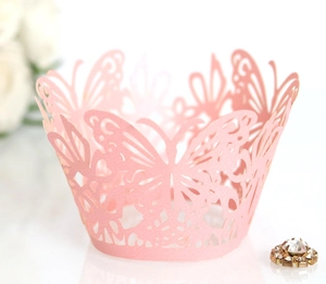 Macro view of laser-cut butterfly cupcake wrapper in soft pink paper for dessert decor