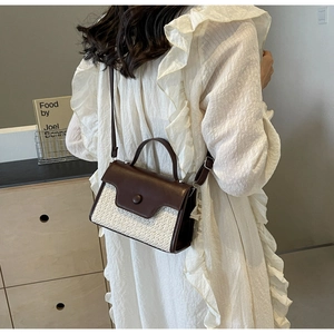 Detail of a woven contrast handbag with brown leather flap and stylish round button ornament