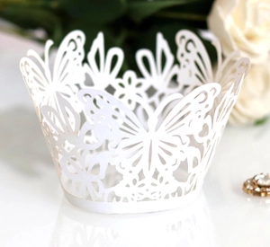 Close-up of laser-cut white paper cupcake wrappers with butterfly and floral patterns